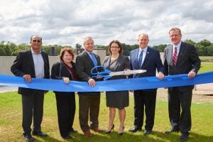American Water Officials standing behind a blue ribbon holding a big pair of scissors