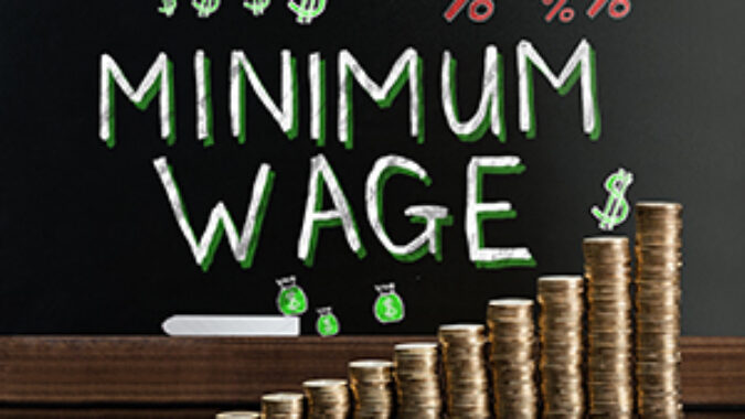 Minimum Wage At Blackboard Behind Stacked Coins