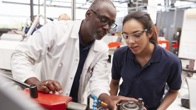 Young woman receives instruction as she works on technical equipment