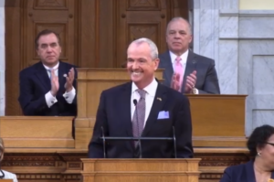 Gov. Phil Murphy delivers his FY 2021 budget address. Behind him, Assembly Speaker Craig Coughlin and Senate President Steve Sweeney applaud..