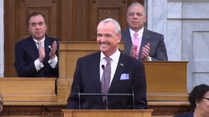 Gov. Phil Murphy delivers his FY 2021 budget address. Behind him, Assembly Speaker Craig Coughlin and Senate President Steve Sweeney applaud..