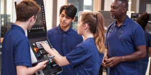 student apprentices receiving instruction on using a high-tech machinery in a shop