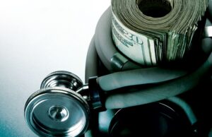 Stethoscope wrapped around a roll of twenty dollar bills