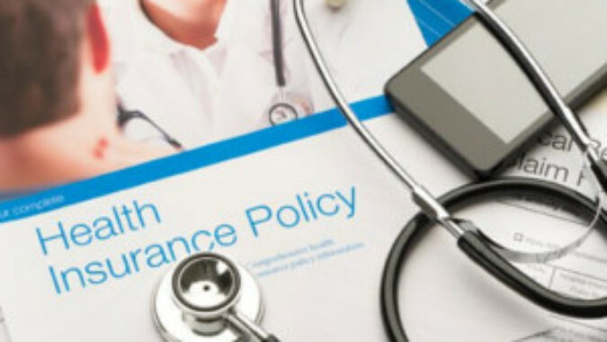 Stethoscope lying on top of a health insurance policy brochure