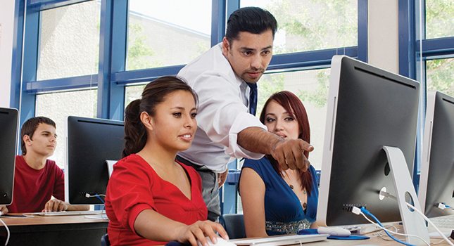 Guy teaching two women on a computer
