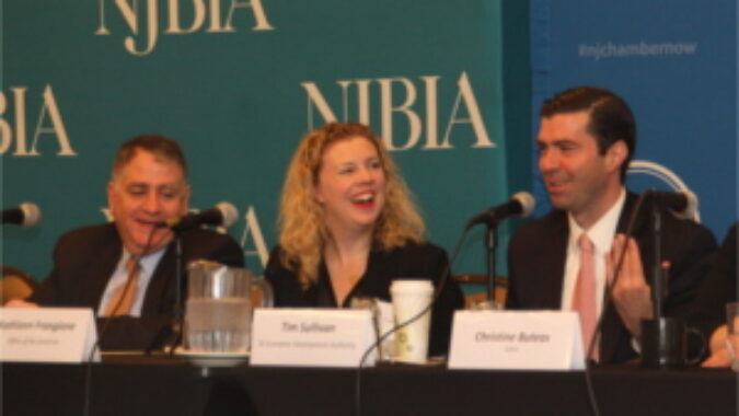 Governor Murphy's key advisors (from left): Chief of Staff Peter Cammarano, Chief Policy Advisor Kathleen Frangione, and Tim Sullivan, CEO of the New Jersey Economic Development Authority at a microphone-covered table and sharing a light moment during panel discussion