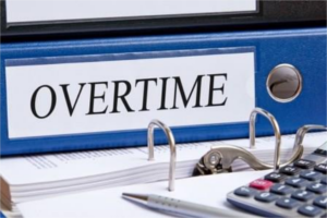 Blue binder labeled Overtime sitting on a desk