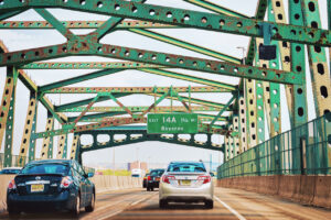 Car driving over a bridge with a NJ exit sign visible