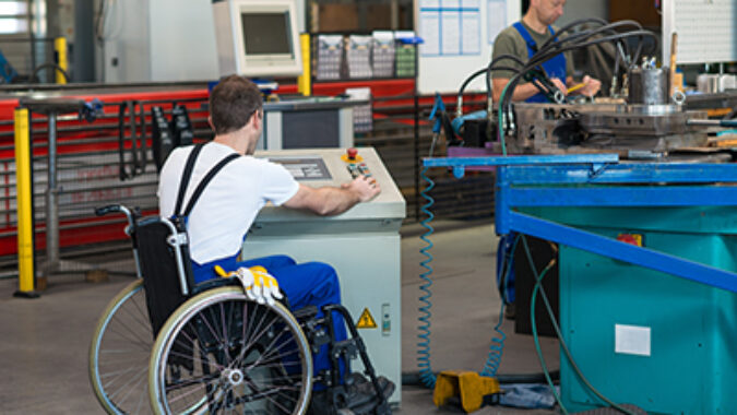 photo of disabled worker in wheelchair in factory on the machine