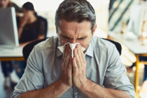 Businessman blowing his nose in an office